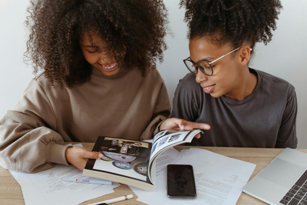 pexels-photo-5234740-5234740 Two young women studying together, using books and technology, focused on learning.