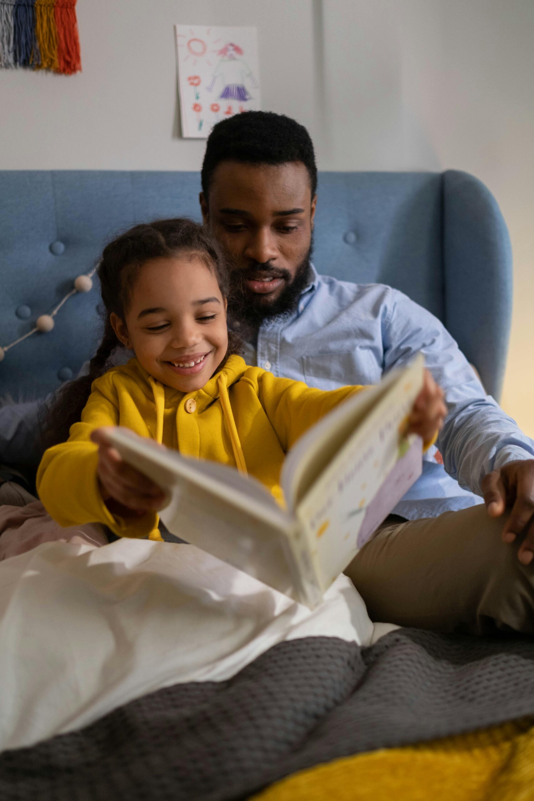 pexels-photo-6595024-6595024 A joyful moment of a father and daughter reading together in a cozy bedroom setting.