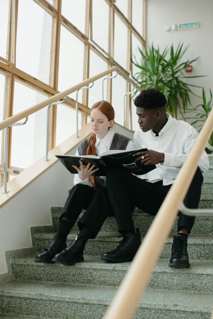 pexels-photo-6279789-6279789 Two young students reading a book on indoor stairs, symbolizing education and diversity.
