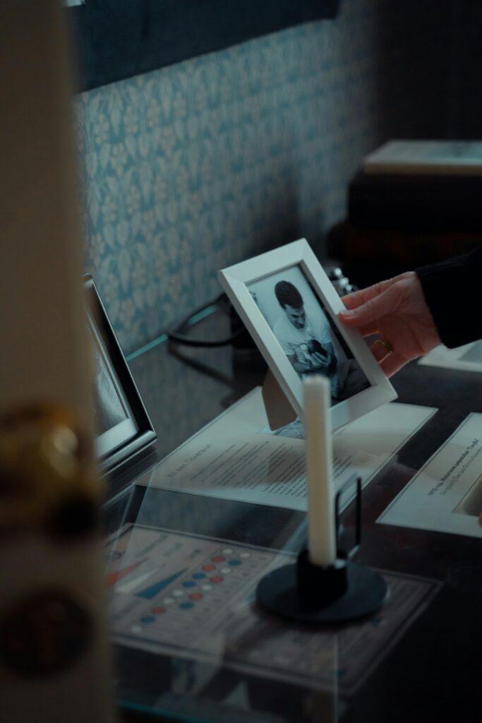 pexels-photo-8861594-8861594 A hand gently touches an old photo frame in a vintage interior setting, evoking a sense of nostalgia and memory.