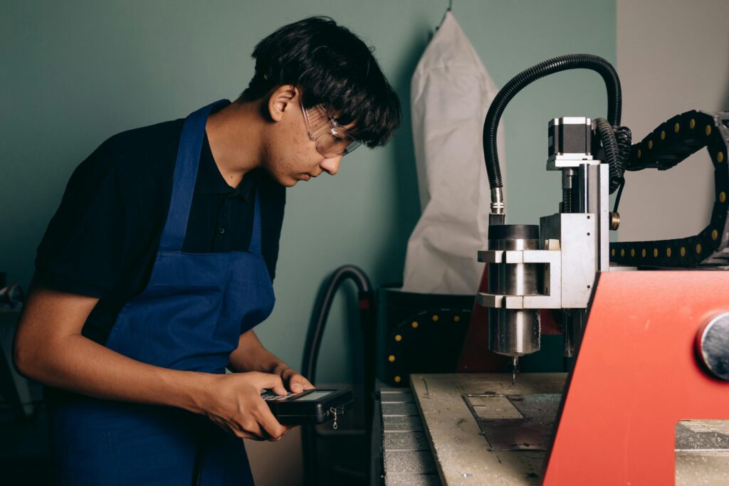 pexels-photo-9242167-9242167 Technician working with CNC machine in an industrial workshop setting, demonstrating concentration and expertise.